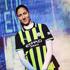 Soccer jersey in yellow and black striped pattern with 'ETIHAD' visible on front. Worn by person against blue digital background.