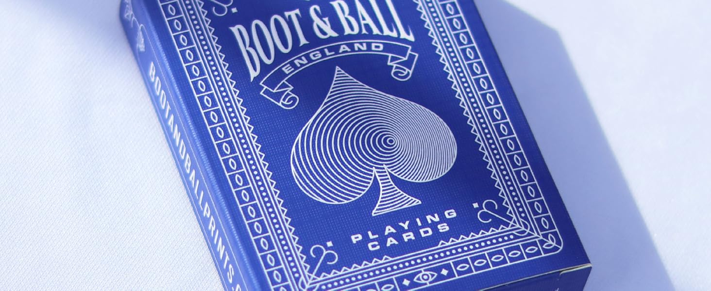 Blue playing card box labeled 'Root & Ball' with white heart design, sitting on white surface casting shadow.