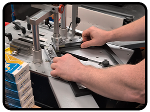 Close-up of hands using a black power screwdriver with various drill bits displayed. Shows detailed bit attachments and operating mechanism.