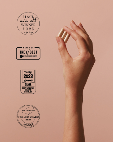 Hand holding a cylindrical product against peach background with multiple award emblems, including H&amp;H winner 2023 and other achievement badges.