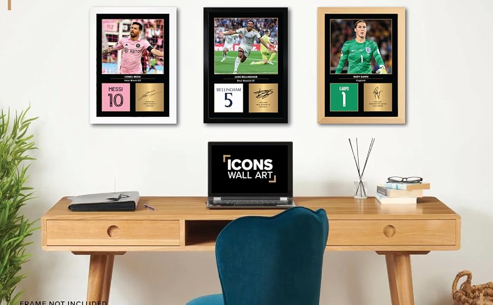 Wooden desk with three framed sports memorabilia, laptop displaying 'ICONS' text, blue chair, and decorative items, showcasing a home office setup.