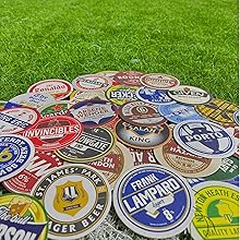 Collection of colorful, vintage beer bottle caps scattered on grass. Various brands and designs visible on caps.